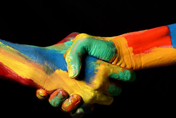 two multi-colored hands shaking and united