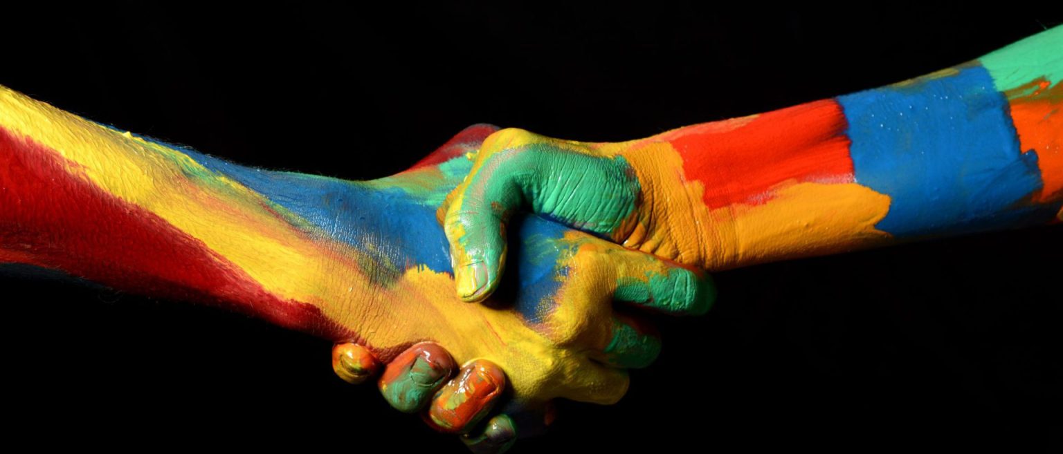 two multi-colored hands shaking and united